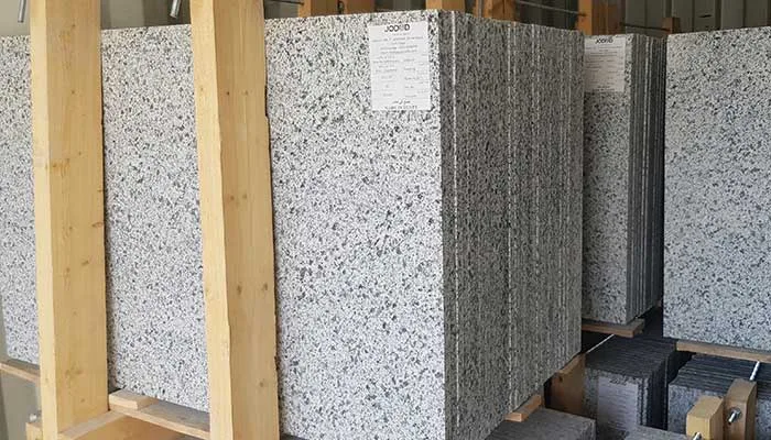 Grey and white granite slabs bundled between timbers with batch labels