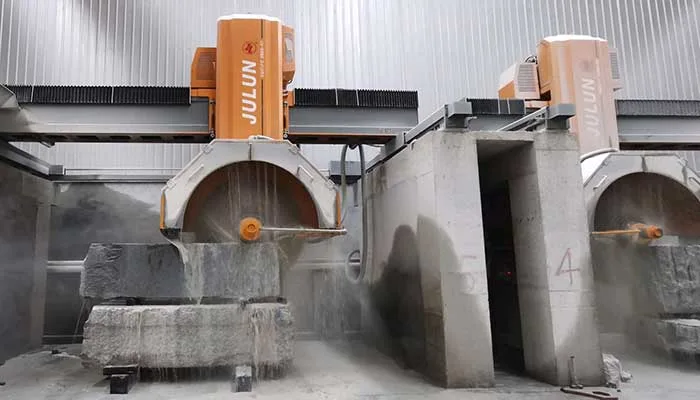 Multi-disc block cutters working grey granite blocks in the dust