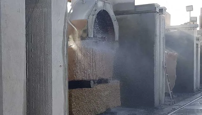 A multi-disc cutter mid-cut through a granite block under water spray