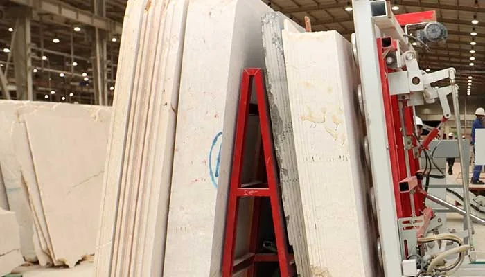 Cream marble slabs standing on A-frames beside the polishing line