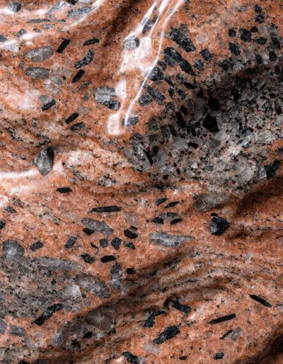 A polished slab of Red Aswan granite, brick-red feldspar flecked with grey quartz and dark mica