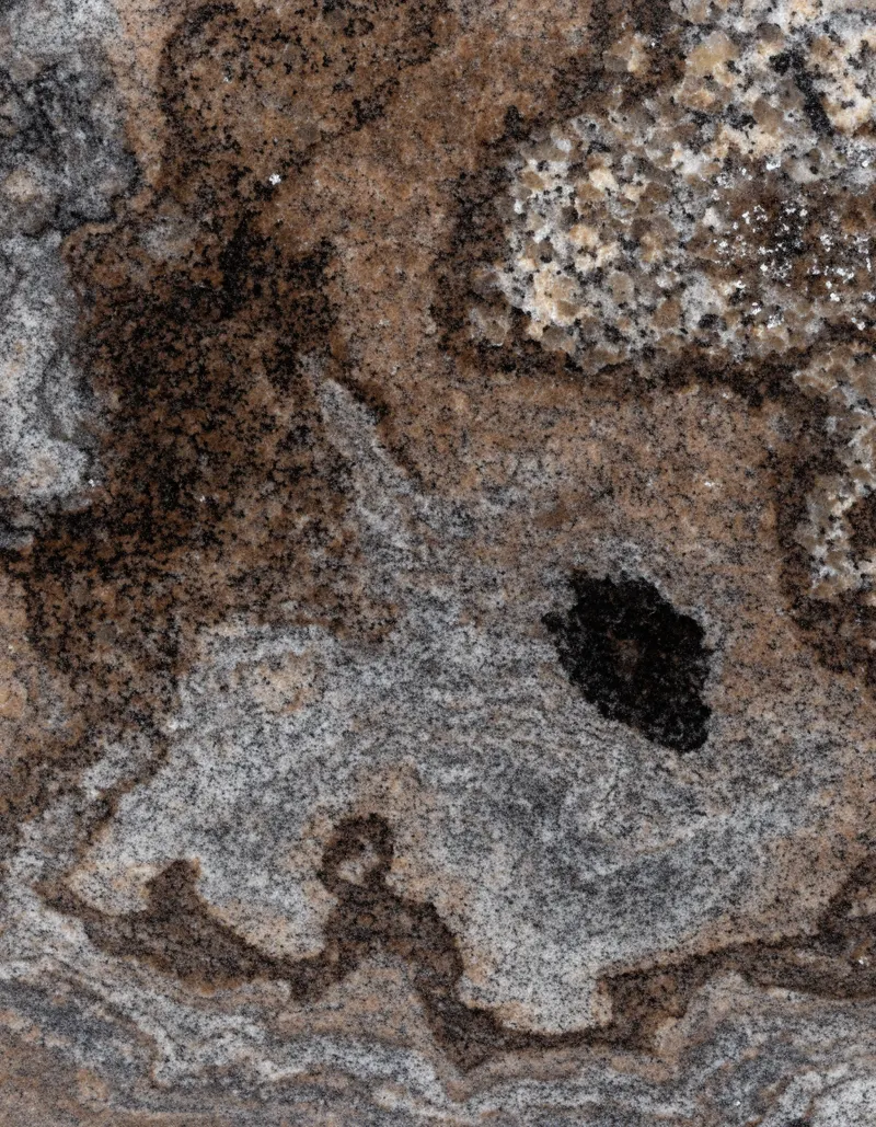 A polished slab of Gandonna Aswan granite, warm mottled patches in strong contrast